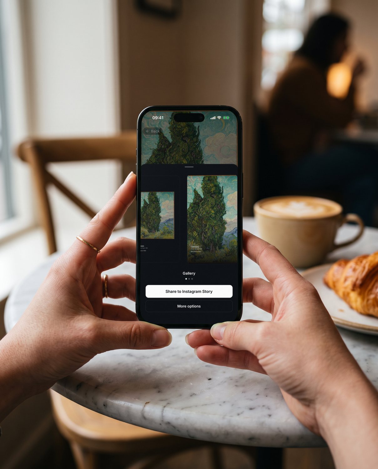 Two hands holding an iPhone in a café, choosing an Instagram Story look for Van Gogh's Cypresses in YEUX.