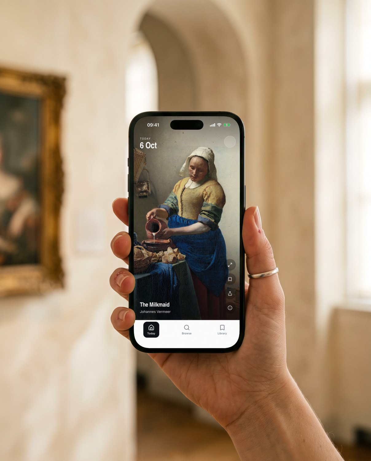 A hand holding an iPhone showing YEUX's Today screen: Johannes Vermeer's The Milkmaid, full screen, in a museum gallery.